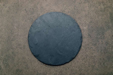 Empty pizza platter for homemade baking set up on dark concrete. Food recipe concept on dark stone background texture with copy space.の写真素材