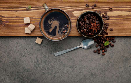 Roasted coffee beans with coffee cup setup on dark stone background.の写真素材