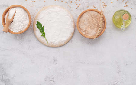 The ingredients for homemade pizza dough with wheat ears ,wheat flour and wheat grains set up on white concrete background.の写真素材