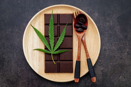 Food conceptual image of  cannabis leaf  with dark chocolate and fork on dark concrete background.の写真素材