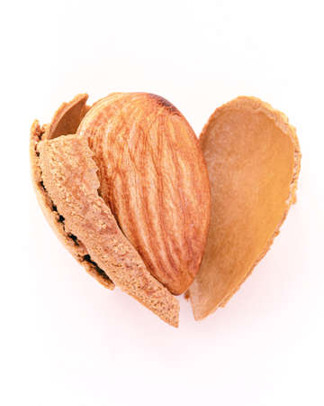 Close up almonds nut shell cracked in heart shape isolated on white background. Love healthy eating concept.の写真素材
