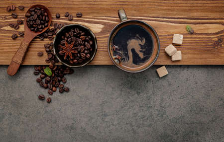 Roasted coffee beans with coffee cup setup on dark stone background.の写真素材