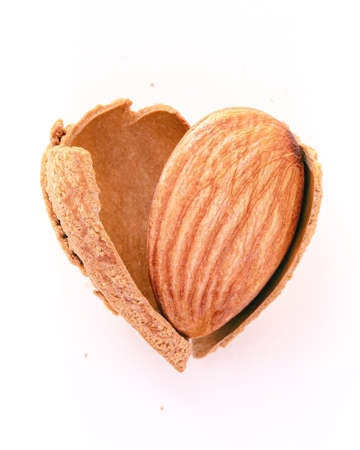 Close up almonds nut shell cracked in heart shape isolated on white background. Love healthy eating concept.の写真素材