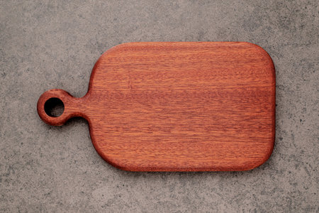 Empty vintage wooden cutting board set up on dark concrete background with copy space.の写真素材