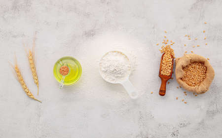 The ingredients for homemade pizza dough with wheat ears ,wheat flour and olive oil set up on white concrete background. top view and copy space.の写真素材