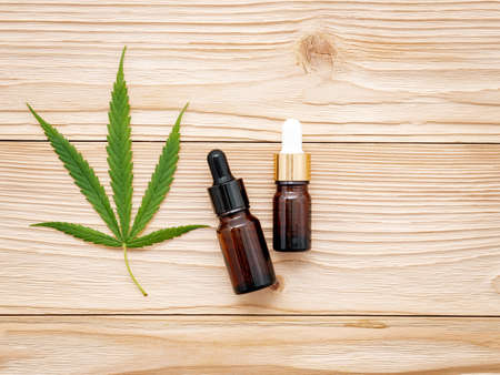 Glass bottle of cannabis oil and hemp leaves set up  on wooden background.の写真素材