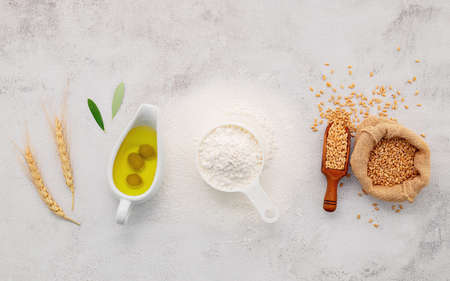 The ingredients for homemade pizza dough with wheat ears ,wheat flour and olive oil set up on white concrete background. top view and copy space.の写真素材