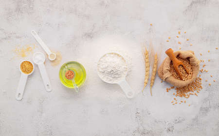 The ingredients for homemade pizza dough with wheat ears ,wheat flour and olive oil set up on white concrete background. top view and copy space.の写真素材