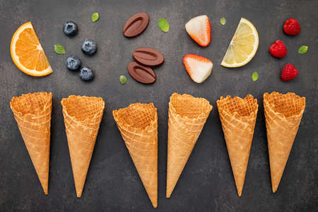Flat lay ice cream cones collection on dark stone background . Blank crispy ice cream cone with copy space for sweets menu design.の写真素材