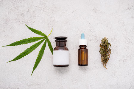 Glass bottle of cannabis oil with  hemp leaves set up  on concrete background.の写真素材