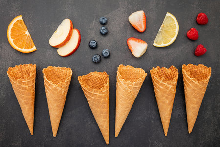 Flat lay ice cream cones collection on dark stone background . Blank crispy ice cream cone with copy space for sweets menu design.の写真素材