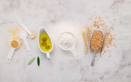 The ingredients for homemade pizza dough with wheat ears ,wheat flour and olive oil set up on white concrete background. top view and copy space.の写真素材
