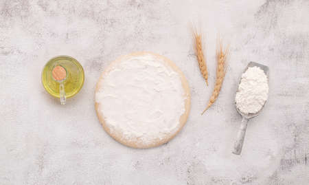 The ingredients for homemade pizza dough with wheat ears ,wheat flour and wheat grains set up on white concrete background.の写真素材