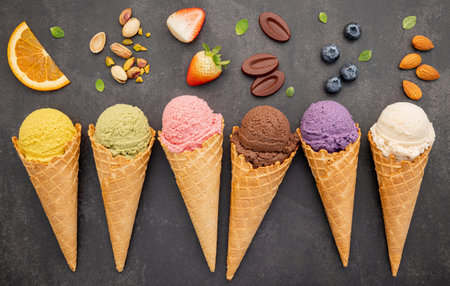 Various of ice cream flavor in cones blueberry ,pistachio ,almond ,orange and chocolate setup on dark stone background . Summer and Sweet menu concept.の写真素材