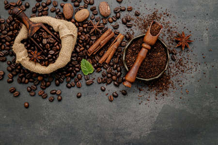 Roasted coffee beans with coffee powder and flavourful ingredients for make tasty coffee setup on dark stone background.の写真素材