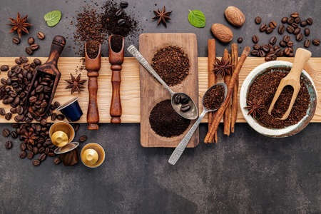 Roasted coffee beans with coffee powder and flavourful ingredients for make tasty coffee setup on dark stone background.の写真素材