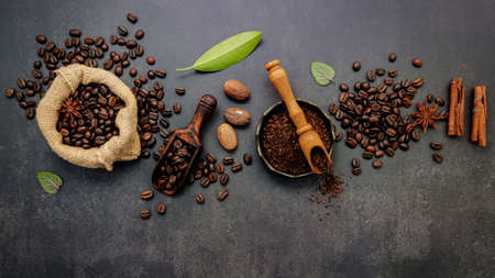 Roasted coffee beans with coffee powder and flavourful ingredients for make tasty coffee setup on dark stone background.の写真素材