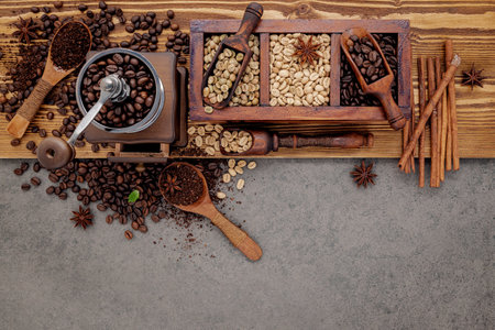 Various of roasted coffee beans in wooden box with manual coffee grinder setup on shabby wooden background.の写真素材
