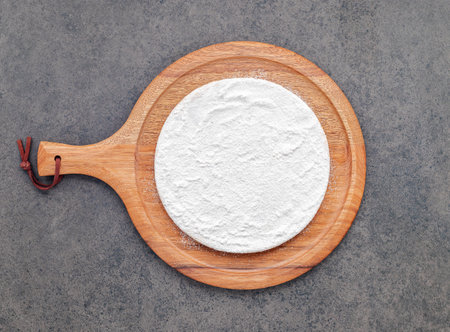 Pizza dough in wooden pizza platter set up on dark concrete. Pizza tray on dark concrete background flat lay and copy space.の写真素材