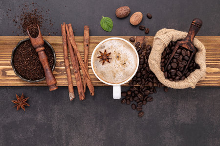Roasted coffee beans with coffee powder and flavourful ingredients for make tasty coffee setup on dark stone background.の写真素材