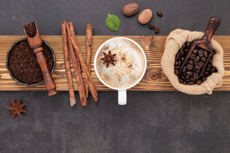 Roasted coffee beans with coffee powder and flavourful ingredients for make tasty coffee setup on dark stone background.の写真素材