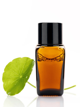 Close up centella asiatica extract in amber bottle with centella asiatica leaves isolated on white background.の写真素材