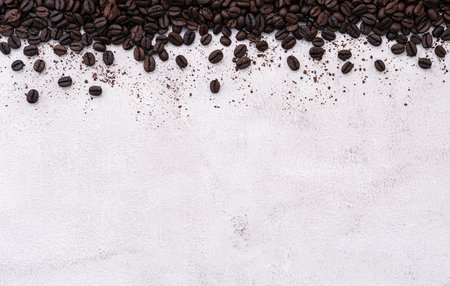 Dark roasted coffee beans setup on white concrete background with copy space.の写真素材