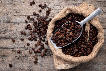 Background of dark roasted coffee beans with scoops setup on wooden background with copy space.の写真素材