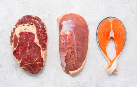 Steak concept with salmon  steak, rib eye steak and duck breast set up on white concrete background.の写真素材