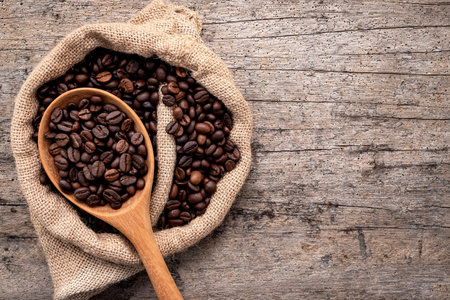 Background of dark roasted coffee beans with scoops setup on wooden background with copy space.の写真素材