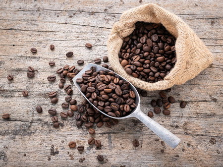 Background of dark roasted coffee beans with scoops setup on wooden background with copy space.の写真素材