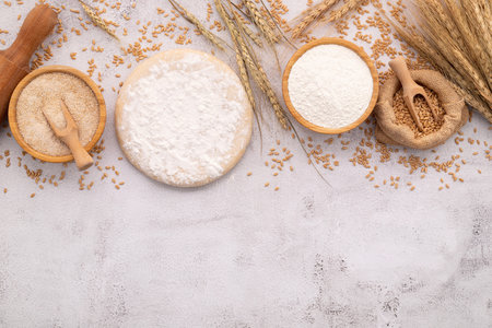 The ingredients for homemade pizza dough with wheat ears ,wheat flour and wheat grains set up on white concrete background.の写真素材