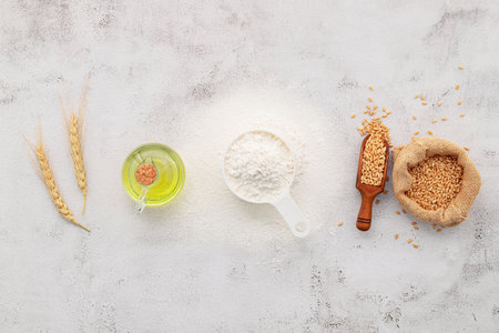 The ingredients for homemade pizza dough with wheat ears ,wheat flour and olive oil set up on white concrete background. top view and copy space.の写真素材