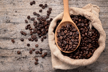 Background of dark roasted coffee beans with scoops setup on wooden background with copy space.の写真素材