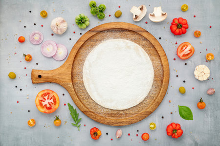 The ingredients for homemade pizza with wooden pizza tray set up on grey concrete background. top viewの写真素材