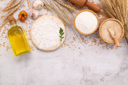 The ingredients for homemade pizza dough with wheat ears ,wheat flour and wheat grains set up on white concrete background.の写真素材