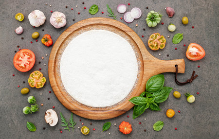 The ingredients for homemade pizza set up on dark stone background.の写真素材