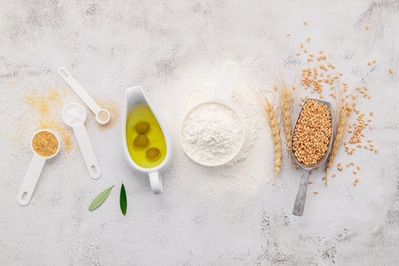 The ingredients for homemade pizza dough with wheat ears ,wheat flour and olive oil set up on white concrete background. top view and copy space.の写真素材