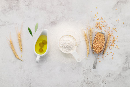 The ingredients for homemade pizza dough with wheat ears ,wheat flour and olive oil set up on white concrete background. top view and copy space.の写真素材