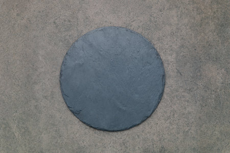 Empty pizza platter for homemade baking set up on dark concrete. Food recipe concept on dark stone background texture with copy space.の写真素材