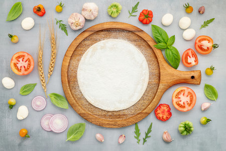 The ingredients for homemade pizza with wooden pizza tray set up on grey concrete background. top viewの写真素材