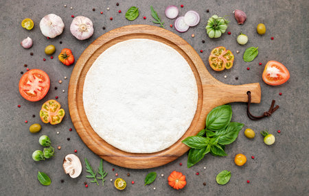 The ingredients for homemade pizza set up on dark stone background.の写真素材
