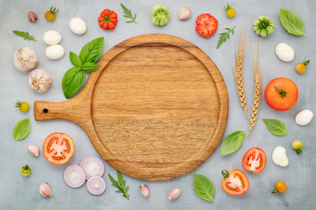The ingredients for homemade pizza with wooden pizza tray set up on grey concrete background. top viewの写真素材