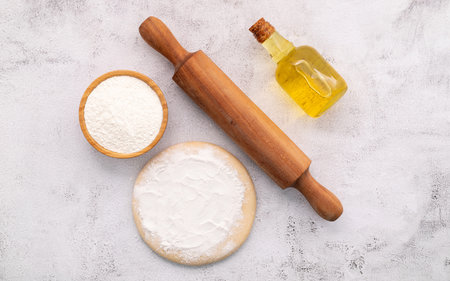 The ingredients for homemade pizza dough with wheat ears ,wheat flour and wheat grains set up on white concrete background.の写真素材
