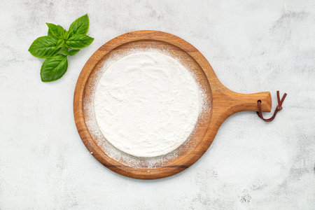 Pizza dough in wooden pizza platter set up on white concrete. Pizza tray on white concrete background flat lay and copy space.の写真素材