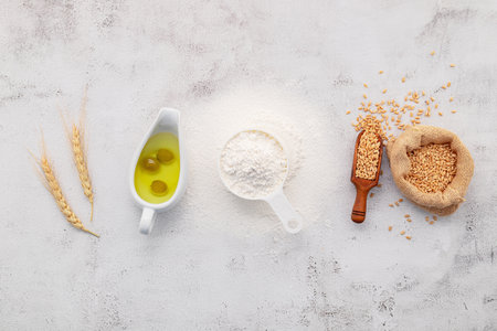 The ingredients for homemade pizza dough with wheat ears ,wheat flour and olive oil set up on white concrete background. top view and copy space.の写真素材