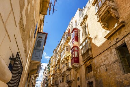 Typical narrow maltese streets with colorful traditional windows and wooden shutters and balconies, clear blue sky on a summer day, Valletta, Maltaの写真素材