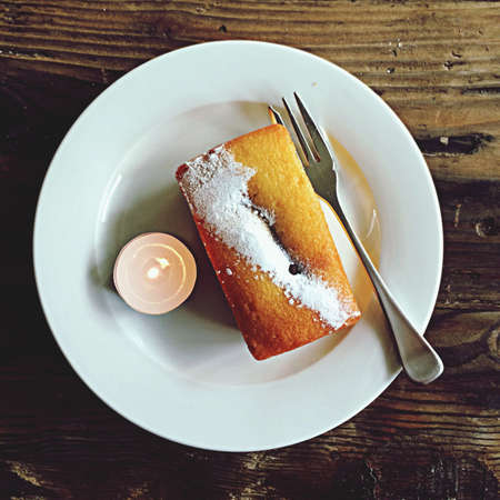 Cake on white plate with fork and candleの素材