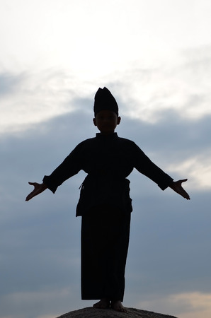Silhouette of young boy performing a pencak silat, Malay traditional discipline martial artの写真素材
