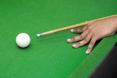 Snooker player with billiard cue ready to hit white ball